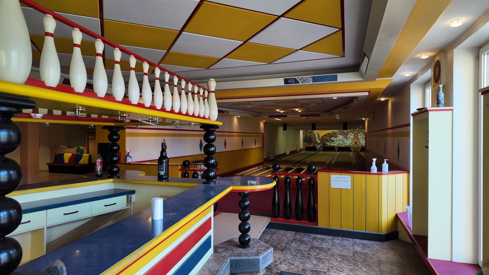 Reihe alter Bowlingkegel als Deko über der alten Bar